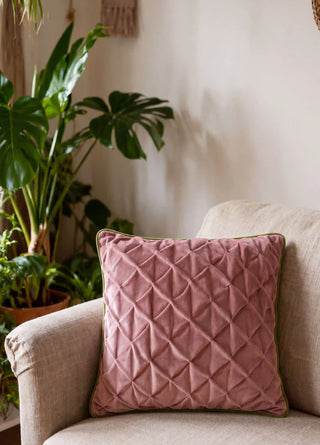 The Prism Lattice cushion cover in Rosewood & Olive styled on a linen armchair beside potted plants.