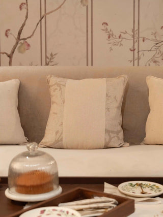 The Prose Pattern cushion cover in beige with a wide cream textured panel and faint tonal branch print, styled on a cream sofa.