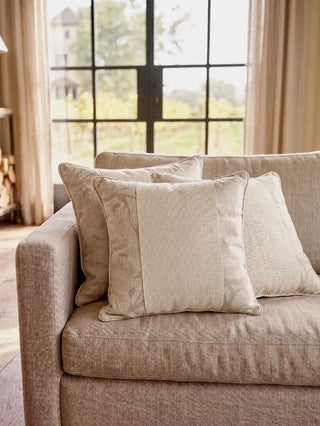 A cluster of Prose Pattern paneled linen cushion covers styled elegantly across a plush contemporary taupe sofa layout.