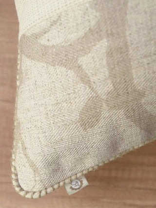 A macro view of the hand-guided whipstitched cord boundary and printed branch fabric on the corner of the Prose Pattern pillow.