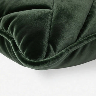 A high-definition close-up showing the plush diamond quilted texture of the forest green velvet cushion.