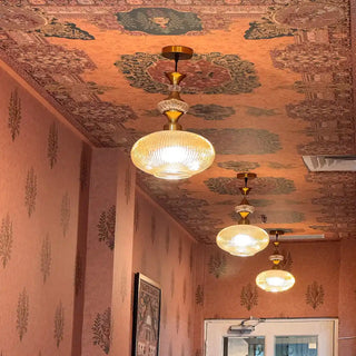 A perspective shot showing the wallpaper’s repeating medallion motifs illuminated by ceiling lights.