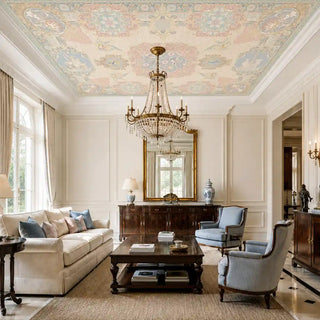 The Rahnuma ceiling mural in Dusty Rose & Gold installed above a formal living room with cream sofas, blue armchairs and a crystal chandelier. view-ceiling