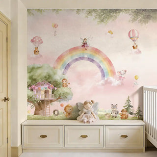 A whimsical watercolor rainbow mural featuring a treehouse and forest animals above a white storage bench in a high-end nursery.