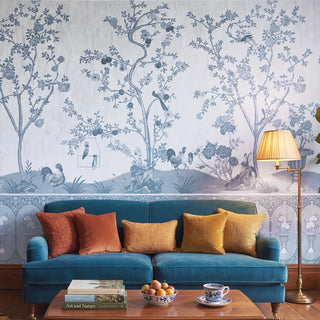 A luxury living room featuring the Raj Bagh wall mural in slate blue behind a teal velvet sofa with ochre and rust pillows view-livingroom