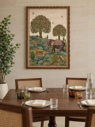 The Rajasi Van wall art in a wavy walnut frame above a dark wood dining table with cane-back chairs and ribbed glassware.
