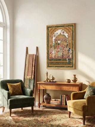 Framed Ram Abhishek embroidered wall art above a wooden console table between two velvet armchairs