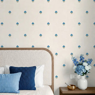 A sophisticated bedroom styling showing the Rani wallpaper paired with a neutral headboard and deep blue textured cushions.