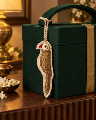 Ranjha embroidered bird charm tied to the handle of an emerald green gift box