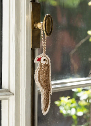 The Ranjha charm in Ivory & Gold, view-doorknob hanging from a brass knob beside a window.