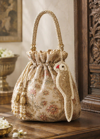 The Ranjha charm in Ivory & Gold, view-potlibag clipped onto an embroidered floral potli bag.
