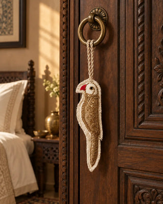 Ranjha ivory and gold embroidered bird charm hanging from an antique brass door handle.