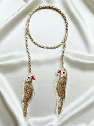 The Ranjha Parrot tieback styled on a cream-colored curtain gathering the fabric elegantly.