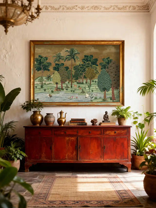 Large Ranthambore Forest wall art in a gold frame styled above a red vintage sideboard with brass vases and indoor plants.