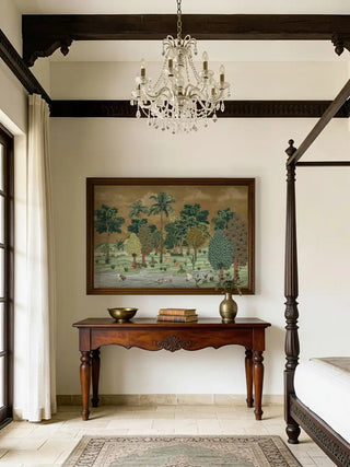 Ranthambore forest art featuring tigers and cranes displayed in a bedroom above a dark wood console table with a crystal chandelier.