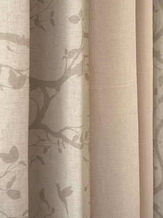 A macro textile shot showcasing the precise jacquard botanical branch patterns and matching open-grid vertical mesh stripes of The Reed Rhythm drape.