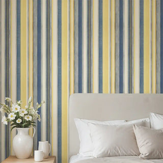Blue and yellow striped wallpaper behind a bed with neutral bedding, creating a vibrant yet sophisticated ambiance.