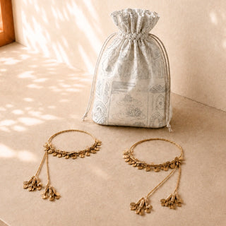Regal Gilt beaded tiebacks styled beside a printed drawstring gift pouch on a sunlit surface