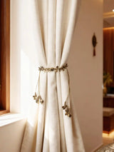Regal Gilt brass-tone leaf and coin charm curtain tieback on cream linen
