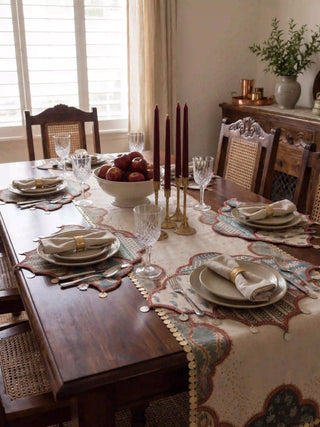 The Riwaayat embroidered table runner styled down a formal wooden dining table with brass candlesticks and burgundy taper candles.