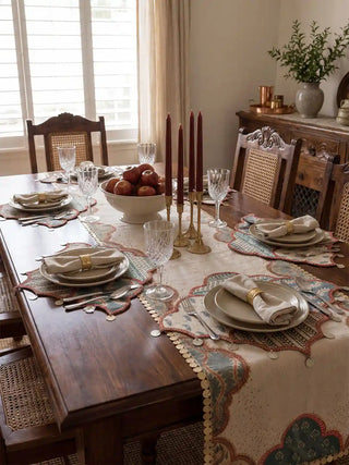 A full festive dining tablescape styled with the Riwaayat luxury table mats, matching runner, fine crystal stemware, and tall crimson candles.