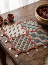 Riwaayat patchwork mats beside terracotta pottery and brass vessels