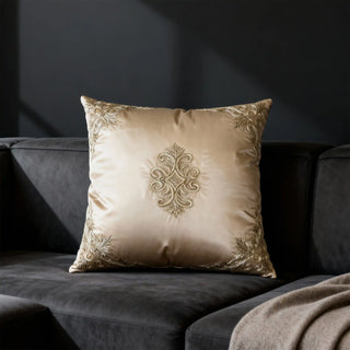 The Rocaille Charm silk cushion cover providing an opulent metallic focal contrast styled across a dark charcoal contemporary leather couch.