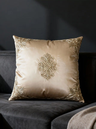 Rocaille Charm cushion cover styled on a charcoal grey velvet sofa featuring central gold scrollwork embroidery.