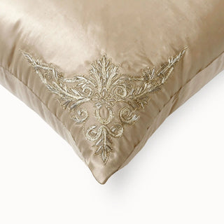 A high-resolution close-up of the champagne silk-satin ground and the intricate gold leaf corner embroidery on the Rocaille Charm cushion cover.