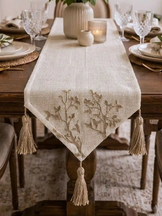 A macro shot highlighting the thick, hand-knotted rustic jute tassel and braided edge piping of the Rooted Grace table runner.