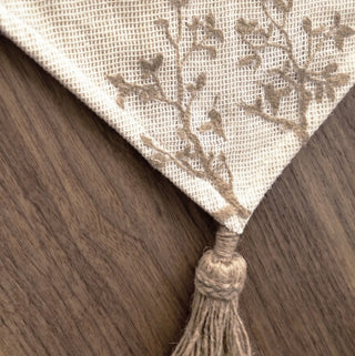 A detailed macro view of the thick, heavy-set natural jute tassel and braided edge piping on the Rooted Grace linens.