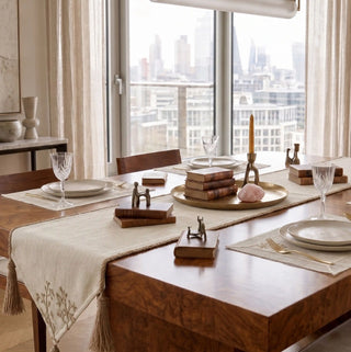 Rooted Grace table runner and matching placemats styled in a high-rise dining room setting with a modern cityscape background.
