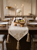 The Rooted Grace organic neutral table runner draping gracefully over the edge of an elegant wooden table setup with crystal glasses.