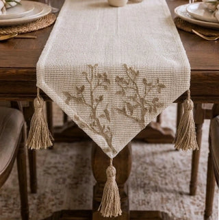 A high-resolution close-up of the open-weave ivory canvas grid and hand-guided taupe tree branch embroidery on the Rooted Grace runner.