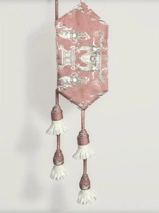 A close-up view of the Rosette Royale tieback showing the neoclassical urn print on rose velvet and tiered tassels.