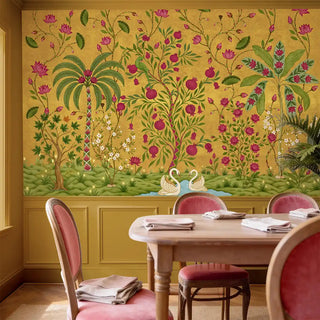A luxury dining room featuring The Royal Bagh ochre mural styled with ochre wainscoting and pink velvet chairs.