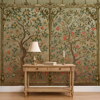A Chinoiserie-style wallpaper featuring intricate tree branches, blooming red and pink flowers, and green foliage framed with ornate borders, styled behind a wooden console and lamp.