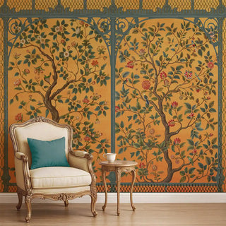 A yellow Chinoiserie wallpaper featuring tree branches with blossoms, green foliage, and ornate borders, styled with a vintage chair and side table.
