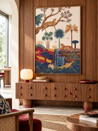 The Royal Jungle Safari wall art, portrait orientation, framed and hung on a walnut panelled wall above a studded wood console with a woven chair in the foreground.