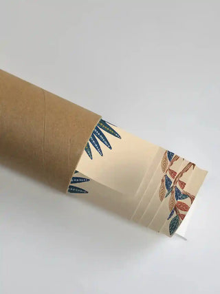 The Royal Jungle Safari wall art partially unrolled from its kraft paper shipping tube, revealing the blue dotwork palm fronds and multi-coloured tree leaves on the parchment ground