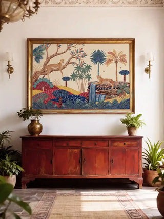 The Royal Jungle Safari wall art in a gilt frame above a distressed red Indian sideboard with a brass urn and terracotta potted plants in a white heritage foyer with plaster cornice and brass wall sconces