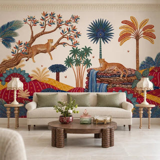 Royal Jungle Safari wallpaper behind a cream sofa with sage-green cushions, a round carved wood coffee table and two scalloped-shade lamps on turned side tables.