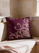 A luxury plum velvet cushion featuring silver-grey vine embroidery and a scalloped edge, styled in a sunlit breakfast nook.