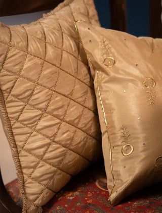 Close-up view of the Rukhsar cushion covers in gold tissue silk showing quilted lattice work, floral butis, and gold piping.