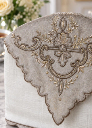 The Rumi tea cosy in Cream, view-detail of scroll-and-floral embroidery on the scalloped overlay.