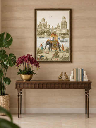 The Safar embroidered wall art above a walnut console with arched panelling, a gold bowl of burgundy orchids, gilt bookends and books.