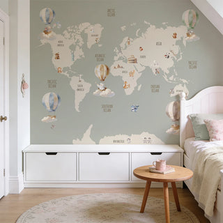 A sophisticated kids' bedroom featuring the sage world map mural above a white storage unit with a wooden side table.