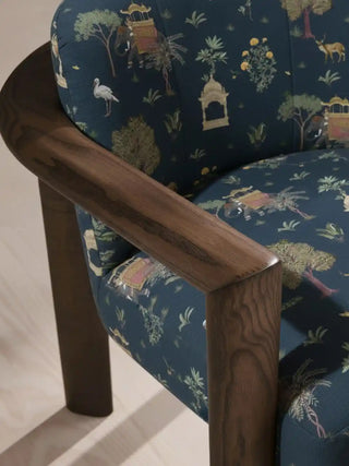 Close up of an armchair upholstered in Sair Blue fabric, highlighting the dark wood arm and the intricate royal procession motifs.