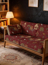 A luxury wooden sofa and cushions upholstered in Sair Red heritage fabric featuring royal elephants and pavilions.