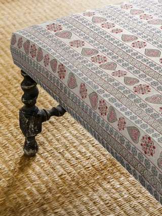 Close up of a luxury bench upholstered in Sarangi fabric, showcasing the traditional motifs against a woven jute rug.